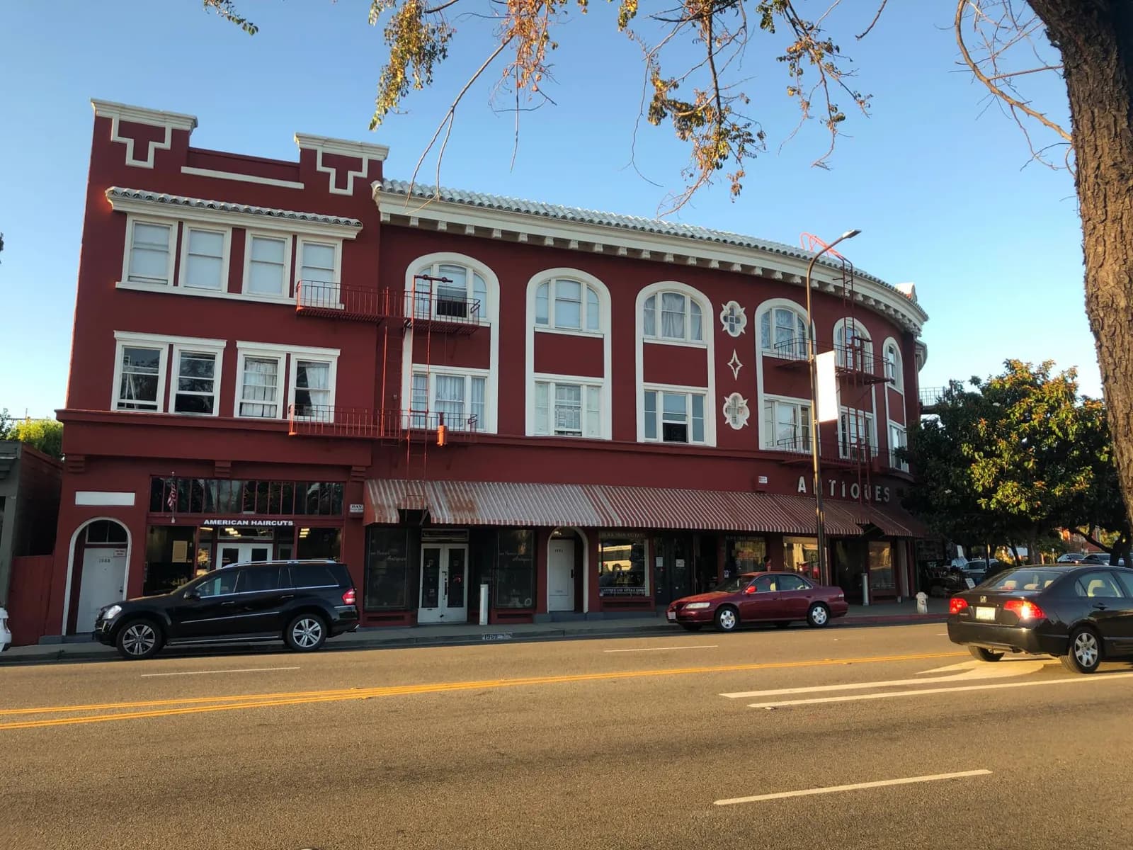 A three-story red brick corner building with shops at street level and apartments above