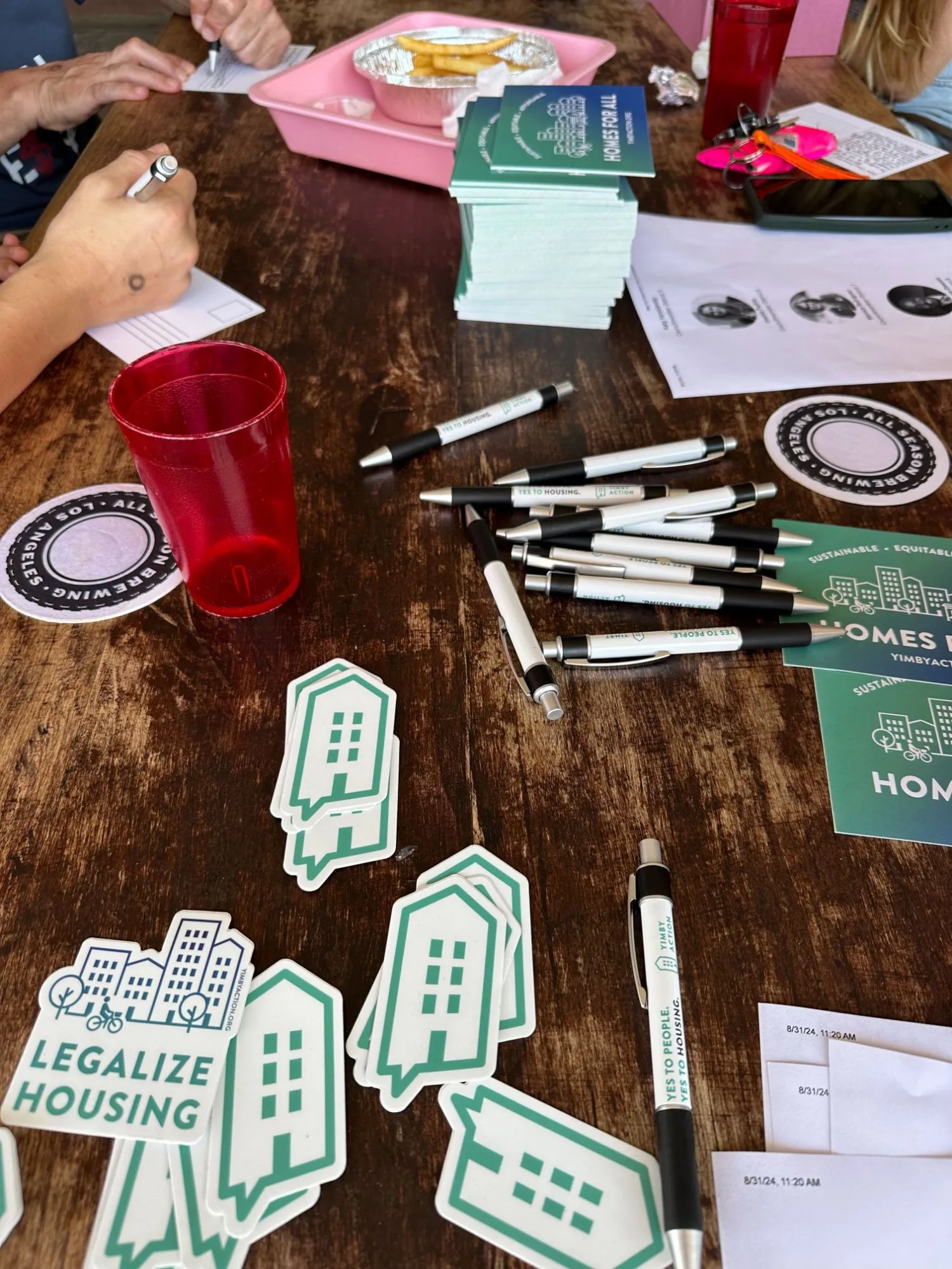 YIMBY Action stickers, pens and postcards spread across a table at a chapter meetup