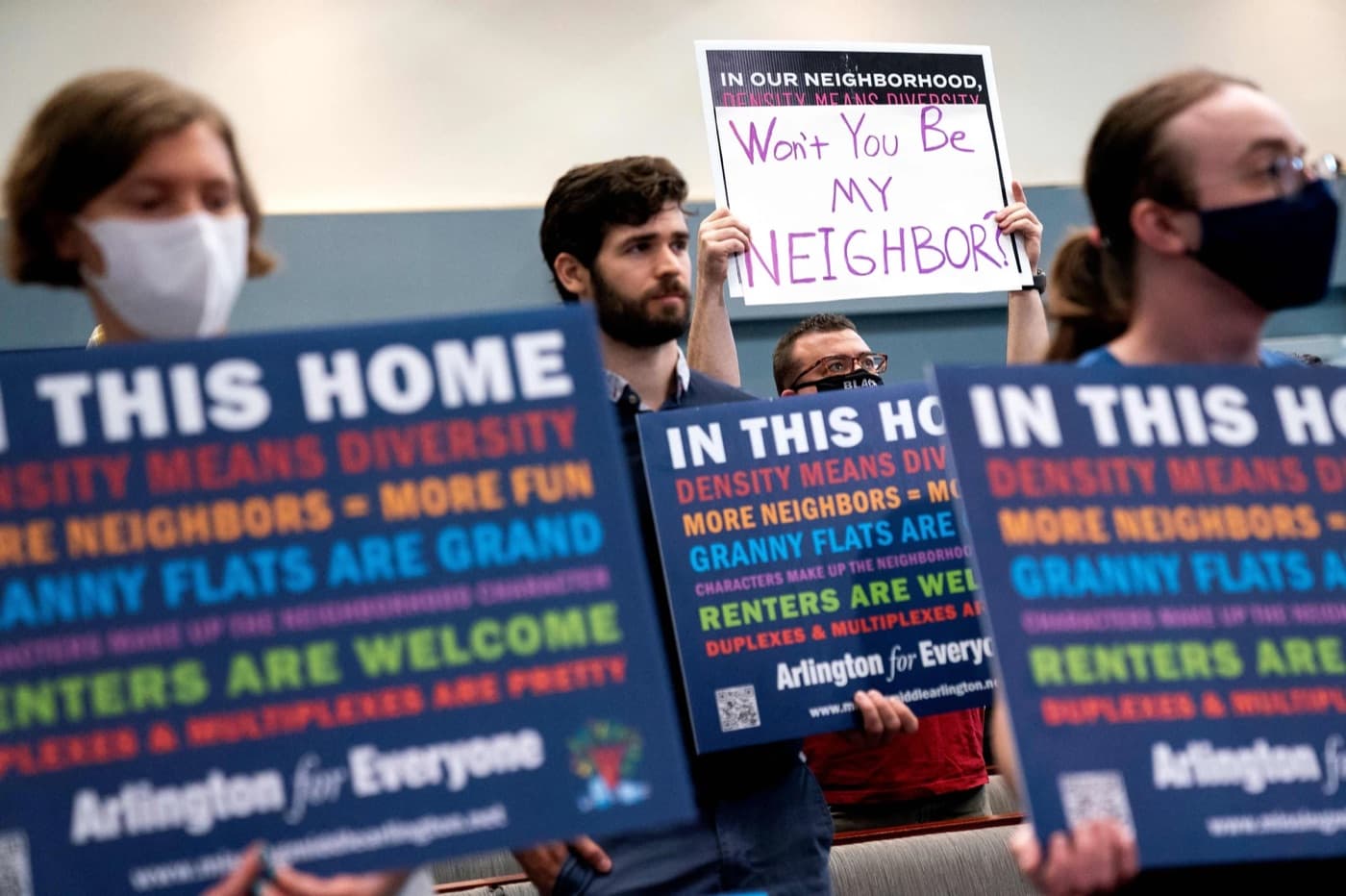 Members holding pro-housing signs at a hearing