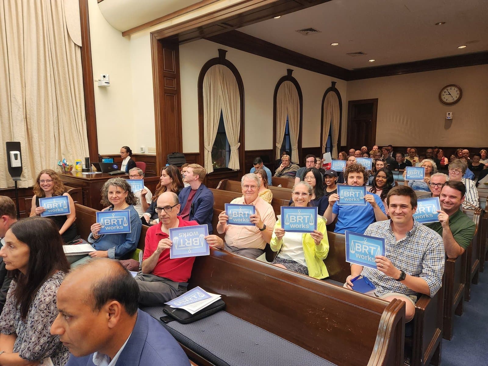 Supporters holding BRT works signs in a packed Alexandria city council chamber