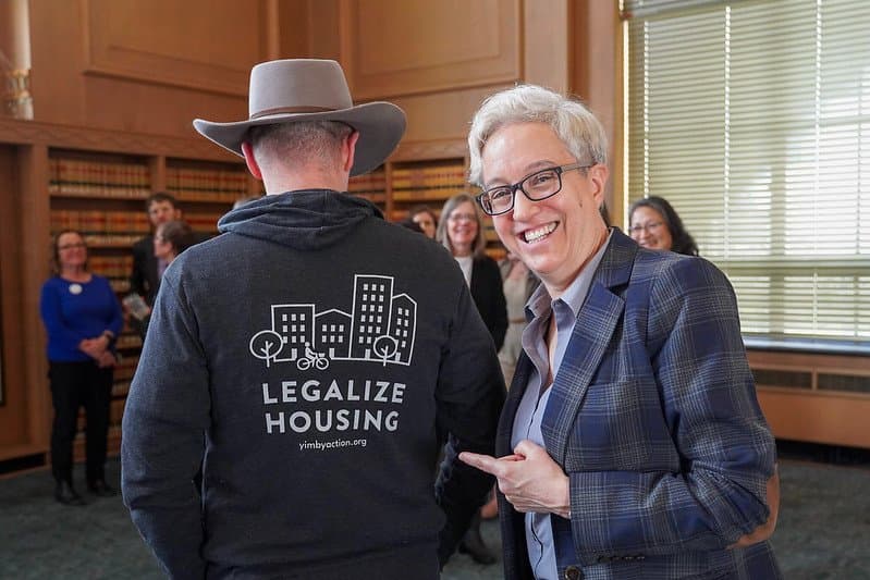 Oregon Governor Tina Kotek pointing at a YIMBY member's Legalize Housing hoodie
