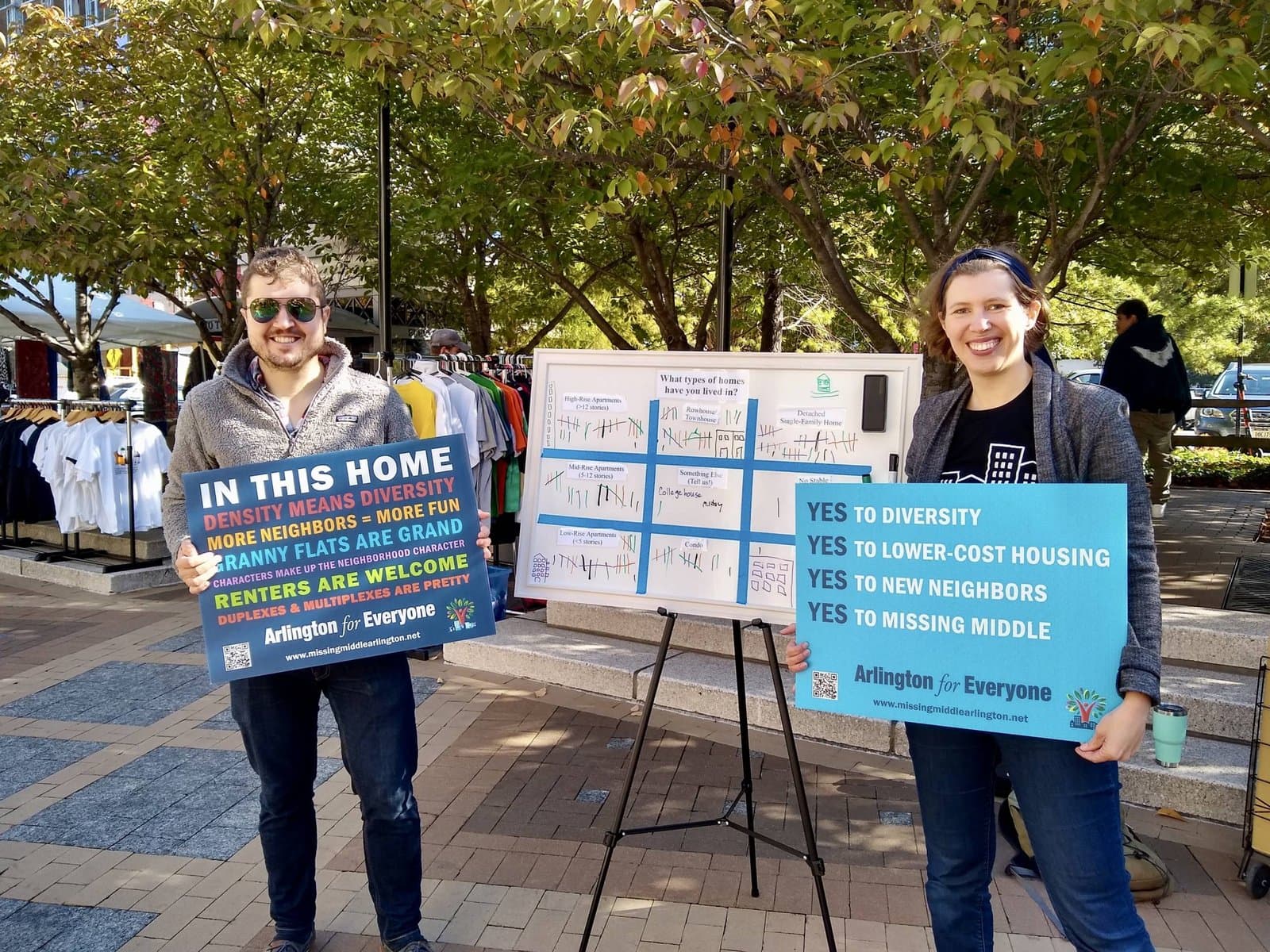 Two Arlington for Everyone volunteers tabling at a street fair with signs reading Yes to missing middle